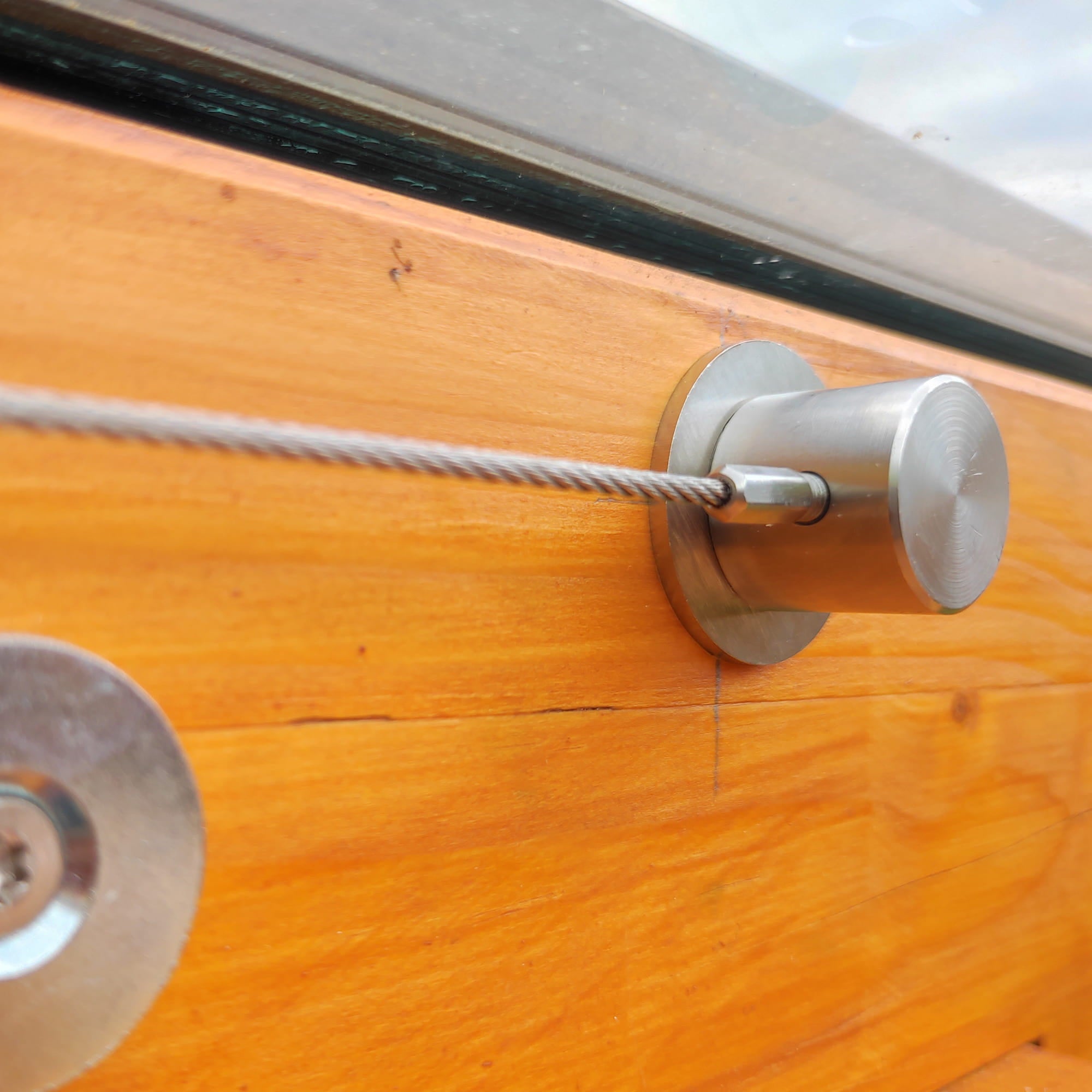 Edelstahlzylinder im Holzdach eines Wintergarten mit Spannseil auf Fundamentteller