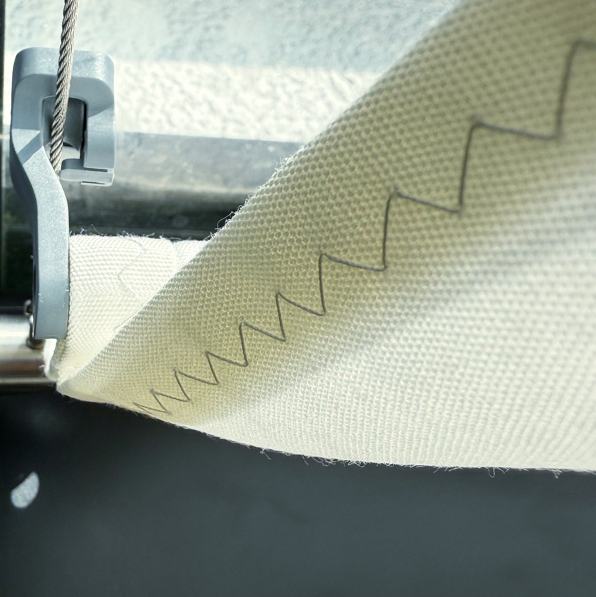 Zick-Zack-Naht in Graphitgrau sichtbar im Aussensaum der SPANNMAXXL-Wolkenbahn uner Spannseil mit Rollpendelhaken